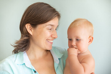 Cute infant baby on mothers hands on a gray background. Mother hugging baby with love. Motherhood concept. Unconditional love