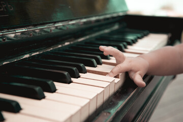Obraz premium The baby's small hand on the piano keyboard