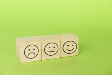 Smiley face, neutral face and sad face. Service score and satisfaction concept on wood block.