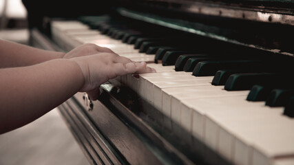 Obraz premium The baby's hand on the piano keyboard