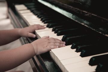 The little girl playing on the piano, close-up 