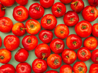 Top view of ripe red acerola cherries fruit. High vitamin C and antioxidant fruits. Close-up and Full-frame photo. Concept of healthy fruits