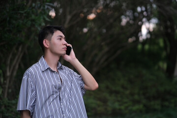 Handsome Asian young man on the phone in natural park