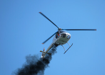 Helicopter with engine problems. Black smoke comes out of the helicopter's engine and the helicopter tries to make an emergency landing. Small helicopter.