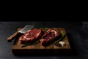 Raw marbled beef steak on a wooden cutting board. Top class marbled beef. Graphite-colored table top.