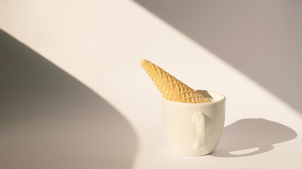 cup of coffee with ice cream cone upside down in it.white background with soft shadows.end of summer and autumn concept idea