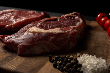 Raw marbled beef steak on a wooden cutting board. Top class marbled beef. Graphite-colored table top.