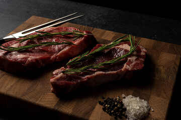 Raw marbled beef steak on a wooden cutting board. Top class marbled beef. Graphite-colored table top.