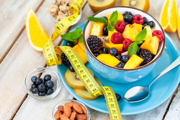 Concept of low calories delicious desserts. Summer fresh bowl with colorful fruit salad. Healthy natural organic food. Tasty sweet snack, light simple tasty lunch. Close up  wooden background