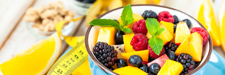 Fototapeta na wymiar Concept of low calories delicious desserts. Summer fresh bowl with colorful fruit salad. Healthy natural organic food. Tasty sweet snack, light simple tasty lunch. Close up wooden background banner