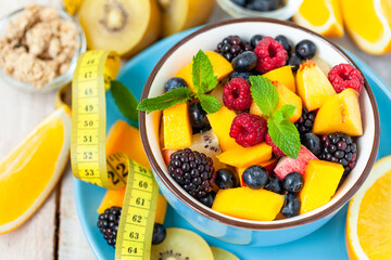 Concept of low calories delicious desserts. Summer fresh bowl with colorful fruit salad. Healthy natural organic food. Tasty sweet snack, light simple tasty lunch. Close up  wooden background