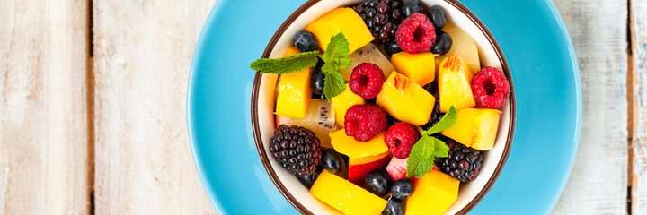 Concept of low calories delicious desserts. Summer fresh bowl with fruit salad. Healthy natural organic food. Tasty snack, light simple tasty lunch. Closeup  wooden background flat lay top view banner