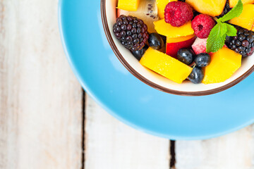 Concept of low calories delicious desserts. Summer fresh bowl with fruit salad. Healthy natural organic food. Tasty snack, light simple tasty lunch. Close up  wooden background flat lay top view