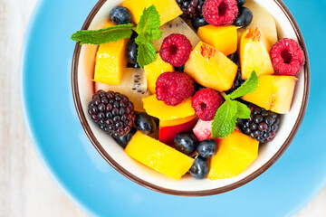 Concept of low calories delicious desserts. Summer fresh bowl with fruit salad. Healthy natural organic food. Tasty snack, light simple tasty lunch. Close up  wooden background flat lay top view
