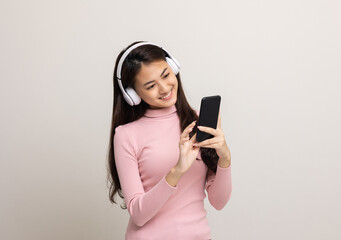 Beautiful young asian women choose song and play music from smartphone connection with wireless headphone having fun in home. Teenage girl listen to the music enjoy relaxing on isolated background.