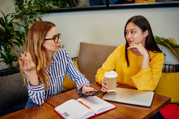 Multiracial students discussing details of project in cafe