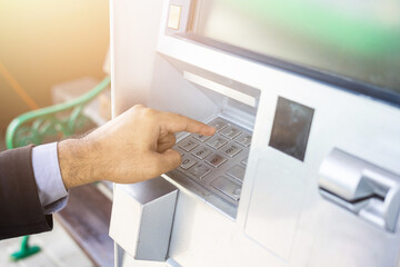 Close up male hand using atm machine withdrawal money. Man put the pin code into bank machine to take the money.