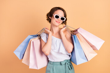 Photo of dreamy adorable woman dressed striped top dark glasses holding shopping bags smiling...