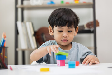 Asian little boy education from home. Developing children's learning before entering kindergarten Practice the skills of playing with wooden toys and drawing and painting.