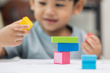 Close up Children hand Practice the skills of playing with wooden toys on the table in living room. Asian little boy education from home. Developing children's learning before entering kindergarten
