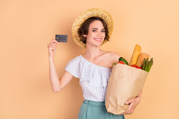 Photo of young girl happy positive smile buy credit card money shopping natural food isolated over beige color background