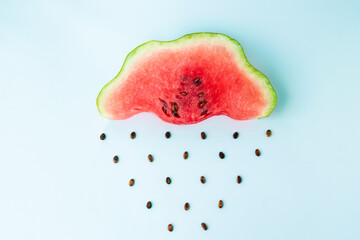 watermelon rain, slice of watermelon in the shape of a cloud with seeds as raindrops. autumn or...