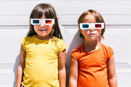 Happy trendy kids in 3D glasses standing on wall