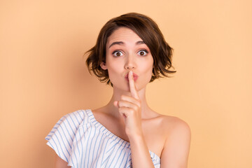Fototapeta premium Photo of young attractive girl cover lips finger shh keep secret confidential isolated over beige color background