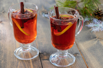 two glasses of hot mulled wine with lemon, cinnamon stick and anise stars. warming drink on cold autumn or winter day.