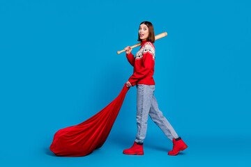 Full length body size photo amazed girl keeping wooden bat big bag with gifts isolated bright blue...