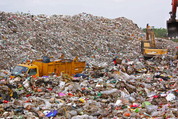 Garbage truck and backhoe working on municipal garbage dump in landfill.
