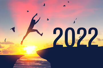 Silhouette man jumping between cliff to 2022 and birds flying at top of mountain. - obrazy, fototapety, plakaty