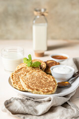 Breakfast with oatmeal pancakes with jam, yogurt and non-dairy milk, light concrete background. Healthy vegetarian food concept.