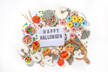 Fototapeta premium Set of various classic Halloween treats on white background. Selection assortment traditional cookies, gingerbread, candy, sweets and decor pumpkins. Trick or treat concept, top view copy space