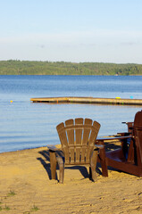 bright yellow Adirondack chair at water’s edge  with blue sky copy space
