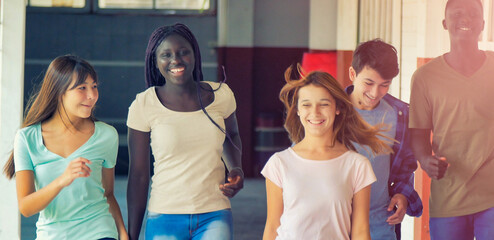 Happy group of multi ethnic teenagers walking in the schoolyard