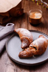 Croissants with caramel and coffee on wooden table. French pastries. Christmas breakfast
