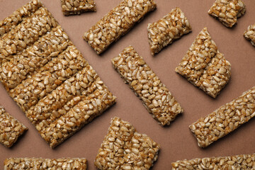 Pieces of delicious kozinaki bars on brown background, flat lay