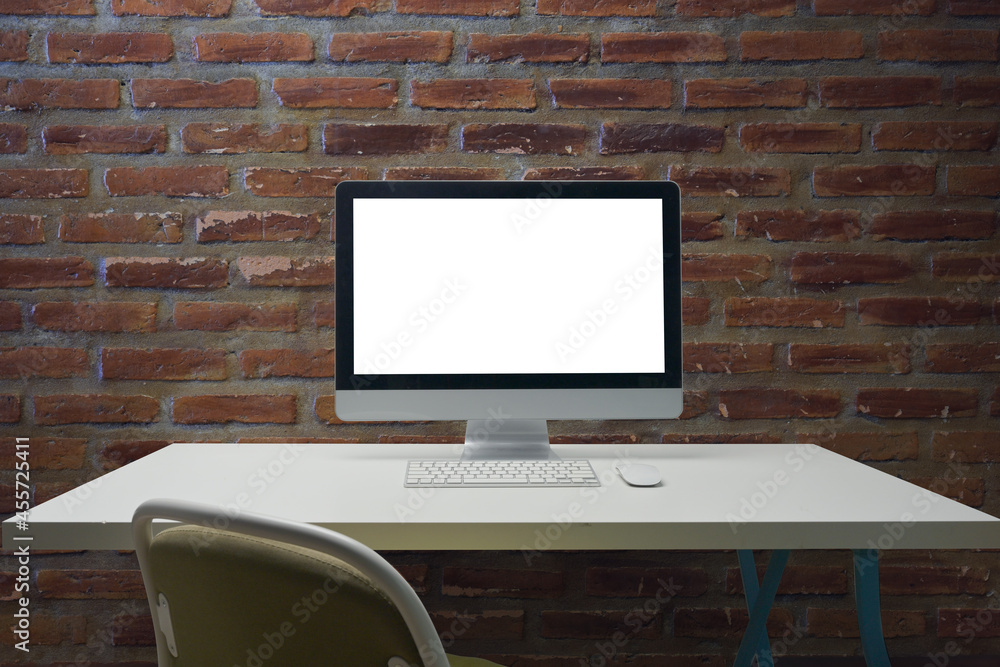 Poster photo of a computer with a white blank screen display putting on working desk over a brick wall as a