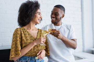 Cheerful african american couple toasting with wine in kitchen.