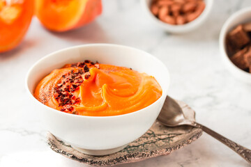 Bowl of tasty pumpkin soup ith chili flakes pepper, nuts and croutons.Space for text on marble table