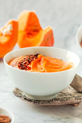 Bowl of tasty pumpkin soup ith chili flakes pepper, nuts and croutons.Space for text on marble table