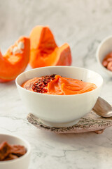 Pumpkin soup and organic pumpkins on marble table. Seasonal autumn food - Spicy pumpkin and carrot soup