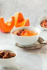 Pumpkin soup and organic pumpkins on marble table. Seasonal autumn food - Spicy pumpkin and carrot soup