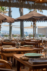 Mesa de restaurante turístico en la playa con copas, vasos, platos y cubertería completa