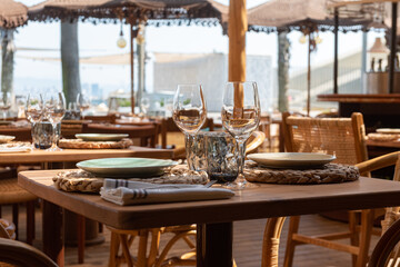 Mesa de restaurante turístico en la playa con copas, vasos, platos y cubertería completa