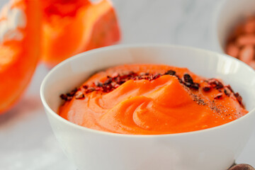 Pumpkin soup with black and chili flakes pepper, rye crispy toast on marble background.Traditional fall and winter dishes. Dietary vegetable food concept.Close-up