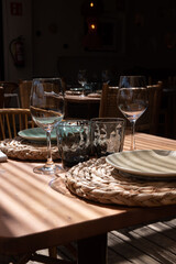 Mesa de restaurante turístico en la playa con copas, vasos, platos y cubertería completa