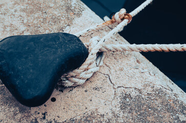black bollard with knotted rope by the sea