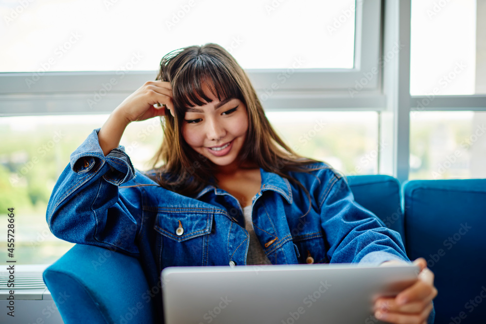 Poster happy asian woman watching positive movie during free time using laptop computer and 4g internet con
